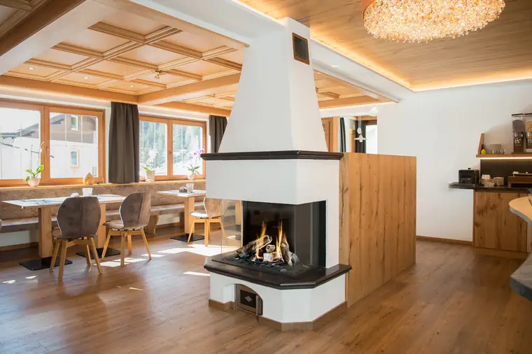 Heller Essbereich mit weißem Eckkamin unter einer Holzdecke