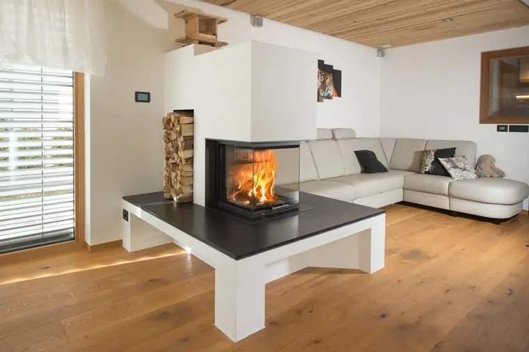 Kamin auf einer weißen Bank mit Holzstapel darunter