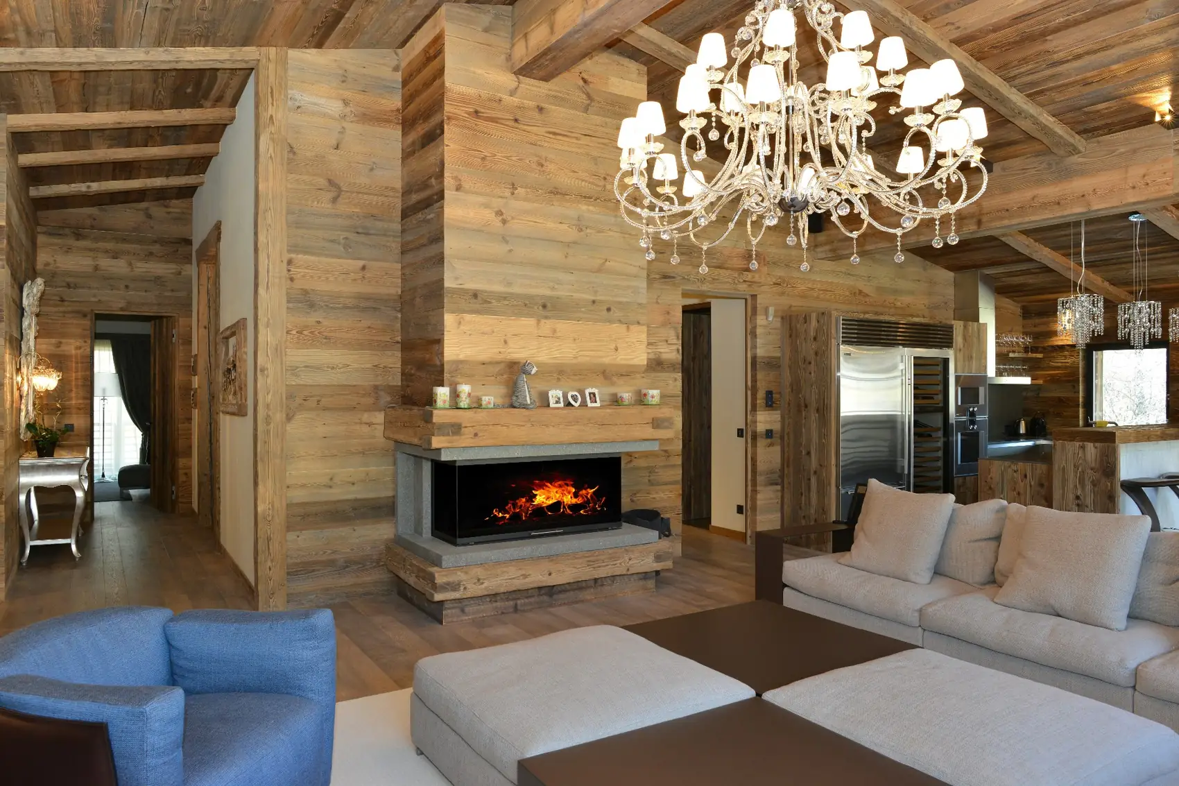 Chalet-Wohnraum mit breitem Kamin unter einer Altholzdecke