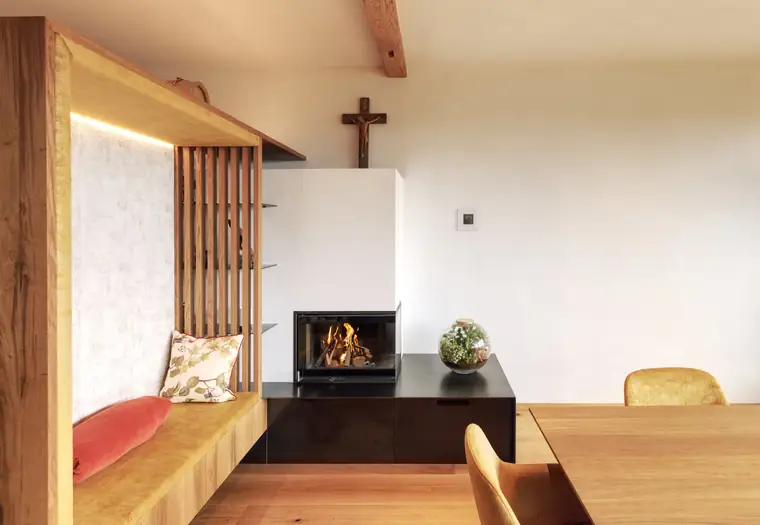 Kamin mit Holzlamellenwand und angesetzter Sitzbank
