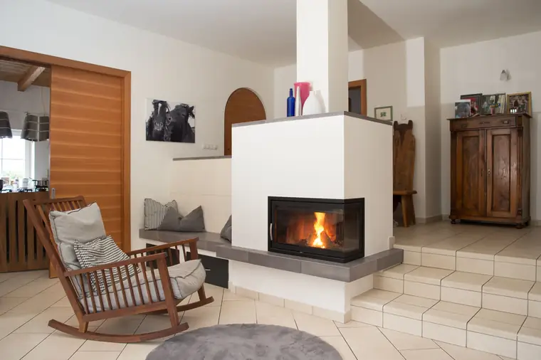 Kamin mit Schaukelstuhl vor einer Holzverkleidung
