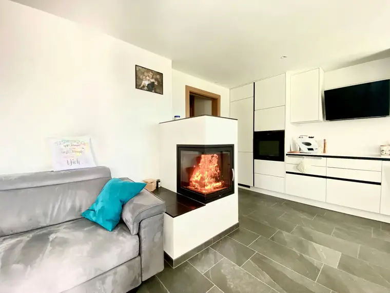 Kaminblock zwischen Sofa und weißer Küche
