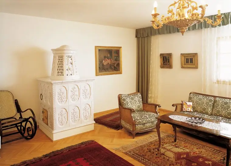 Weißer Stilkachelofen mit Reliefkacheln in einem Salon mit Luster