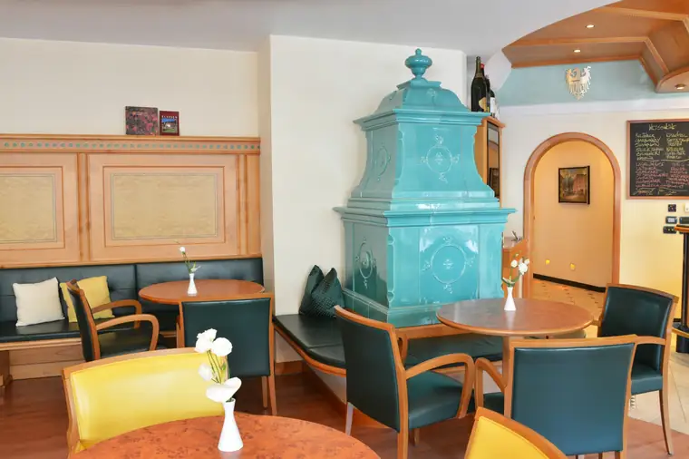 Türkiser historischer Säulenofen in einem Café mit Sitzbänken