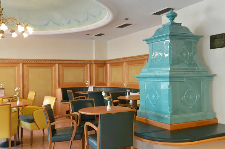 Weite Ansicht des Cafés mit türkisem Säulenofen